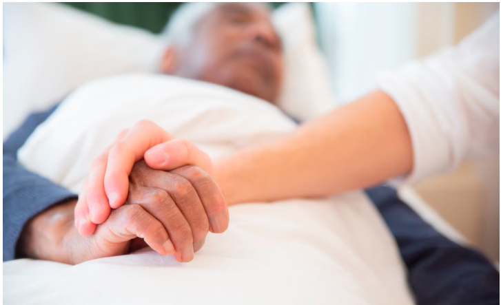 A comforting gesture as a hand holds another in a care bed setting, symbolizing care and support